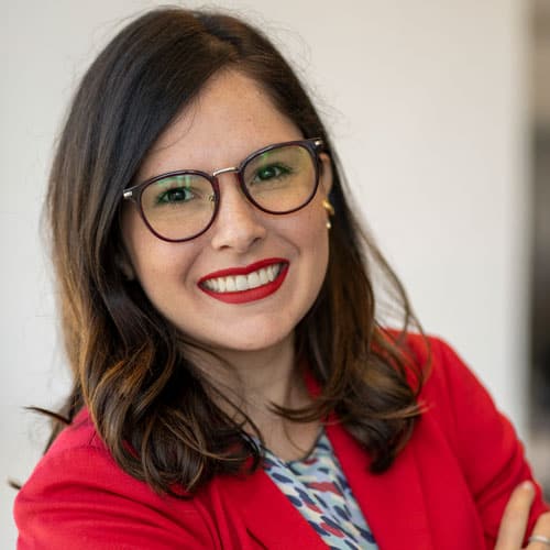 Profissional sorridente com óculos e blazer vermelho, representando liderança e profissionalismo no Instituto Ar.