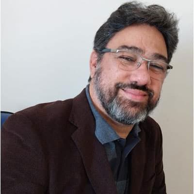 Homem profissional sorridente usando blazer escuro e camisa azul, retrato formal para Instituto Ar.